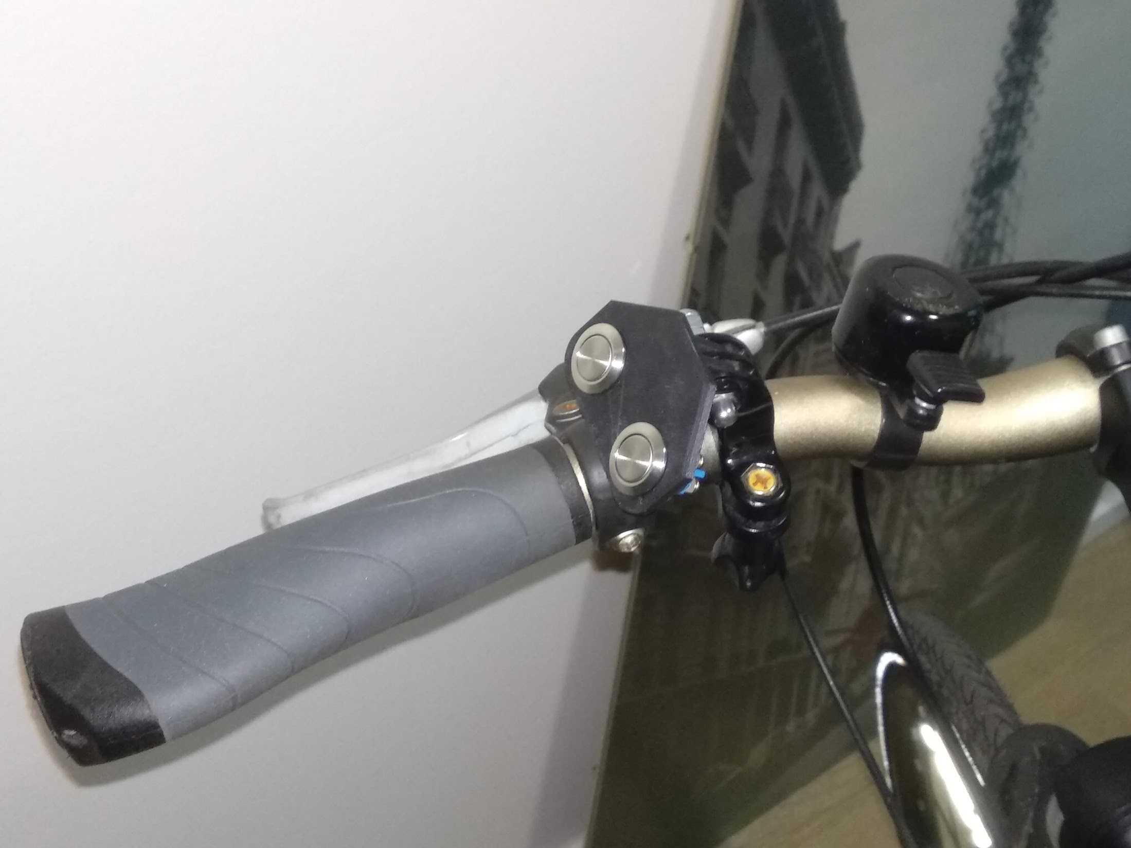 A 3D print with two steel buttons mounted onto a bicycle handlebar